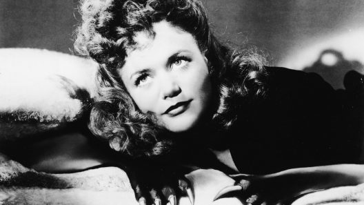 Actor Jane Randolph lays on a bed with feline claws attached to her hands in a still from the film, 'Cat People,' directed by Jacques Tourneur, 1942. (Photo by RKO Pictures/Courtesy of Getty Images)